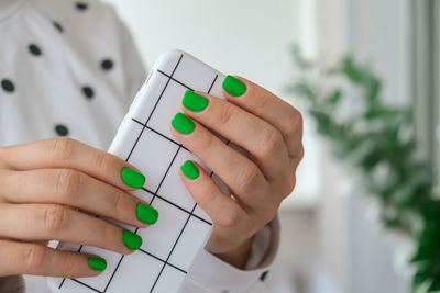 Manicured female hands with stylish green nails holding mobile phone. smartphone technology. trendy 