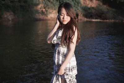 Beautiful young woman standing in lake