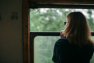 Rear view of woman looking through window in train