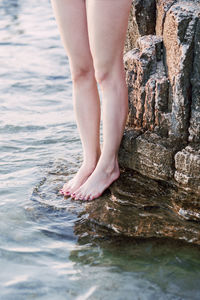 Close up of woman legs standing on the rock by the sea