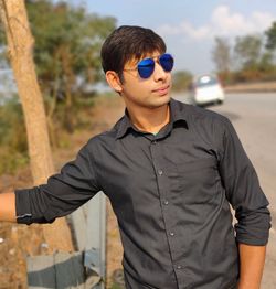Young man wearing sunglasses standing on land