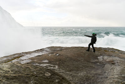 Full length of man standing at sea shore against sky