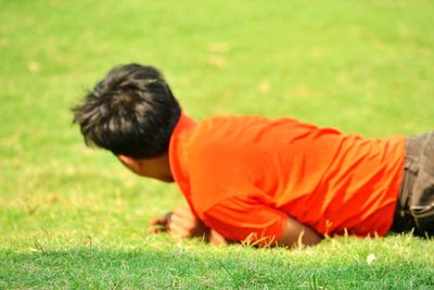 Rear view of boy lying on grassy field