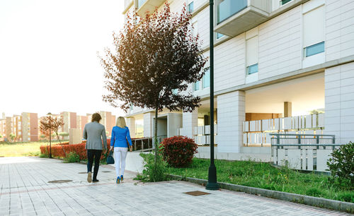 Rear view of people walking by building