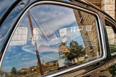 Portrait of man sitting in vintage car seen through window