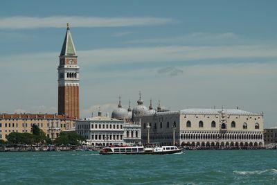 View of buildings at waterfront against cloudy sky