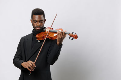 Young woman holding violin against white background