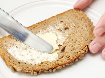 Close-up of hand holding bread in plate