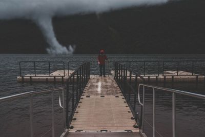 Rear view of man standing on jetty against sea