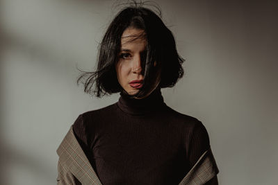 Portrait of beautiful young woman against wall