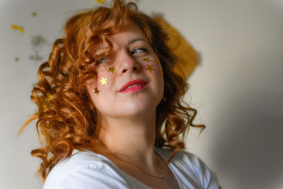 Portrait of young woman looking away against wall