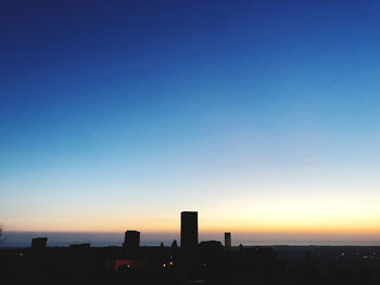 Silhouette buildings against clear sky during sunset