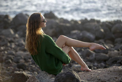 Beautiful woman sitting on rock at beach