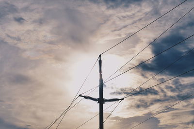 Low angle view of electricity pylon against cloudy sky