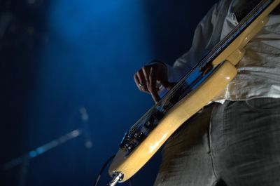 Midsection of man playing guitar in music concert