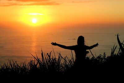 Silhouette woman standing by sea against sky during sunset