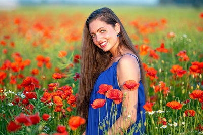 Portrait of young woman amidst yellow flowering plants on field