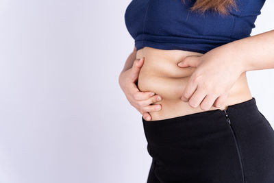 Midsection of woman touching face against white background