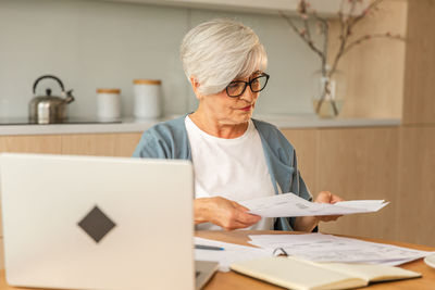 Young woman using digital tablet while working at desk in office