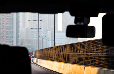 Buildings in city seen from windshield of car on road