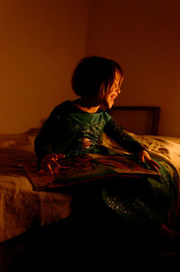 Rear view of woman sitting on floor at home