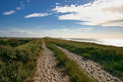 Road amidst field against sky