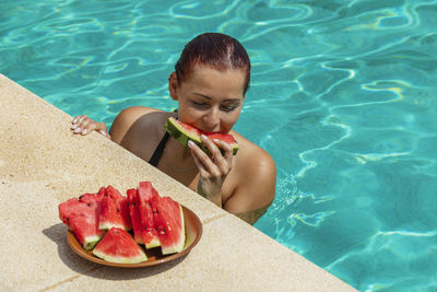 Woman eating food in swimming pool