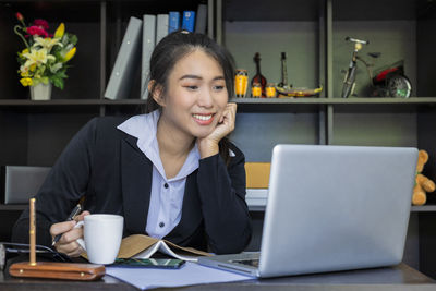 Young woman using phone while sitting on table