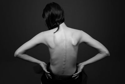 Rear view of woman standing against black background