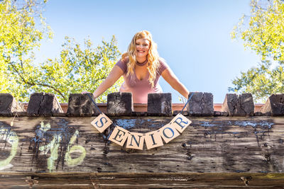 Portrait of smiling teenage girl with message standing on terrace