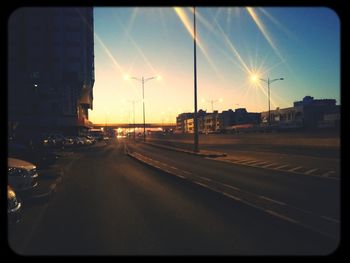 Road passing through city at sunset