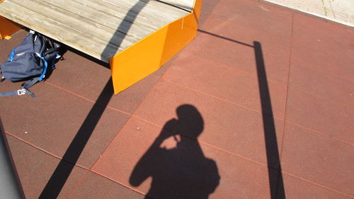 High angle view of shadow of person talking on footpath during sunny day