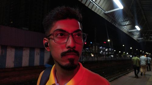 Portrait of young man looking away against building