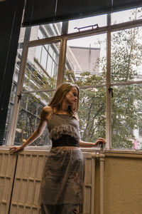 Young woman standing against window