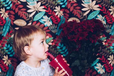 Close-up of cute girl drinking juice while looking at flowers