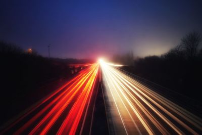 Light trails on highway against sky during sunset