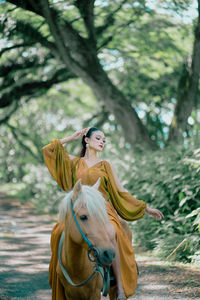 Portrait of young woman with horse standing outdoors