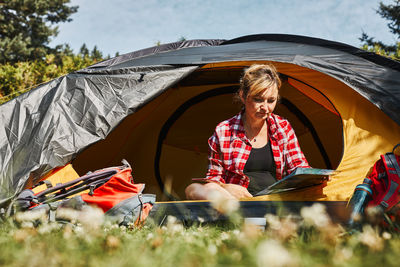 Woman planning next trip while sitting with map in tent. spending vacations. concept of camp life