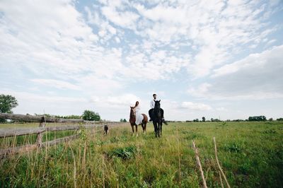 Couple riding horse on field