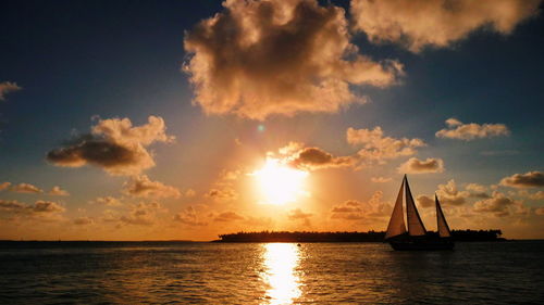 Silhouette sailboat sailing on sea against sky during sunset