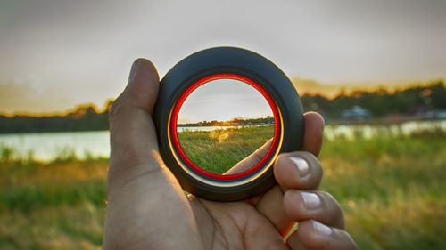 Close-up of hand holding sunglasses against sky