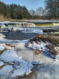 Scenic view of frozen river amidst trees during winter