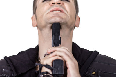 Close-up portrait of young man holding camera against white background