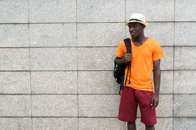 Full length of young man standing against wall