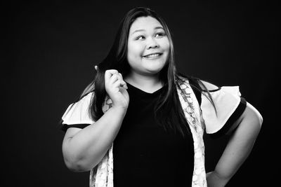 Portrait of smiling young woman against black background