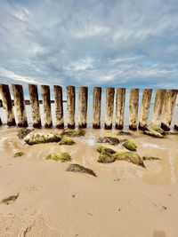 Panoramic shot of wooden posts on beach against sky