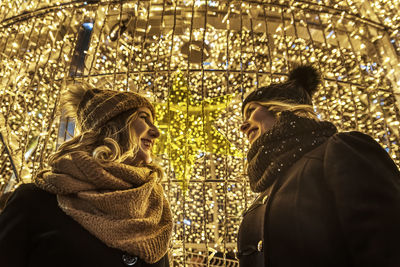 Two young girls are laughing in the background of christmas lights