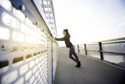 Side view of man on footbridge against sky