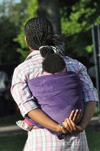 Rear view of mother piggybacking baby at park