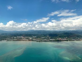 Aerial view of city by sea against sky